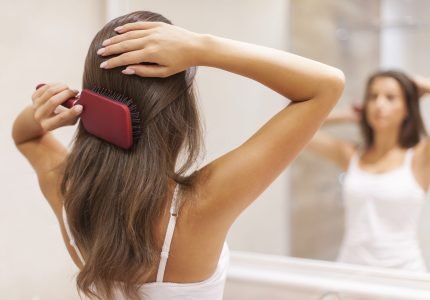 Young woman brushing healthy hair in front of a mirror